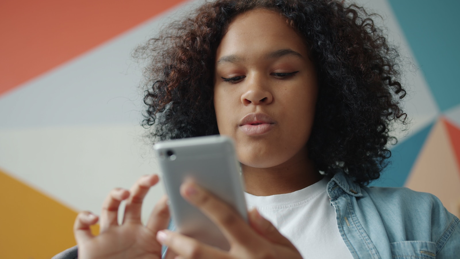 Young woman looking at her smartphone with colorful background.