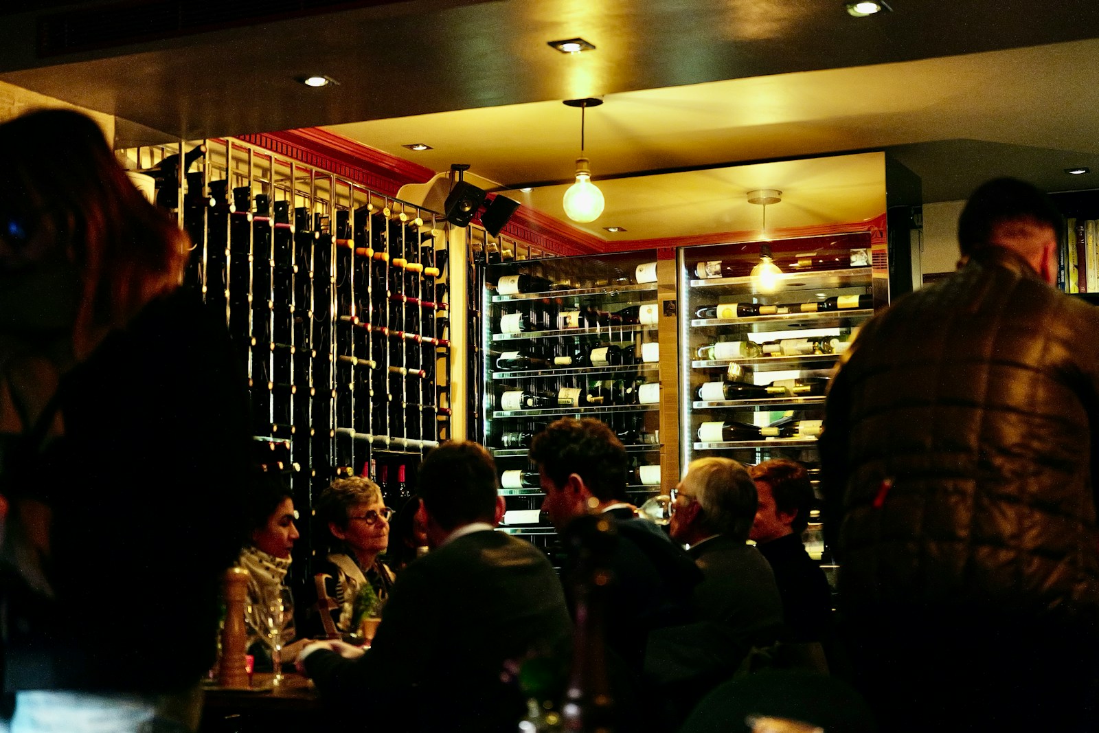People dining in a restaurant with wine racks.
