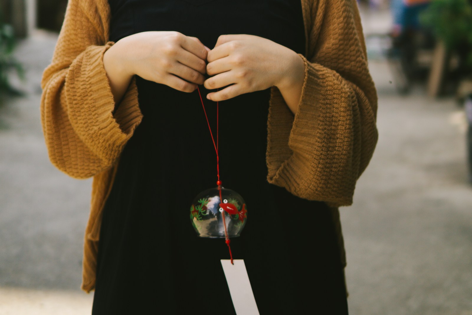 woman in brown sweater holding red and silver ball