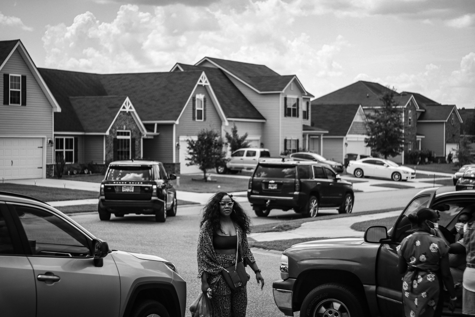 grayscale photo of woman standing near car
