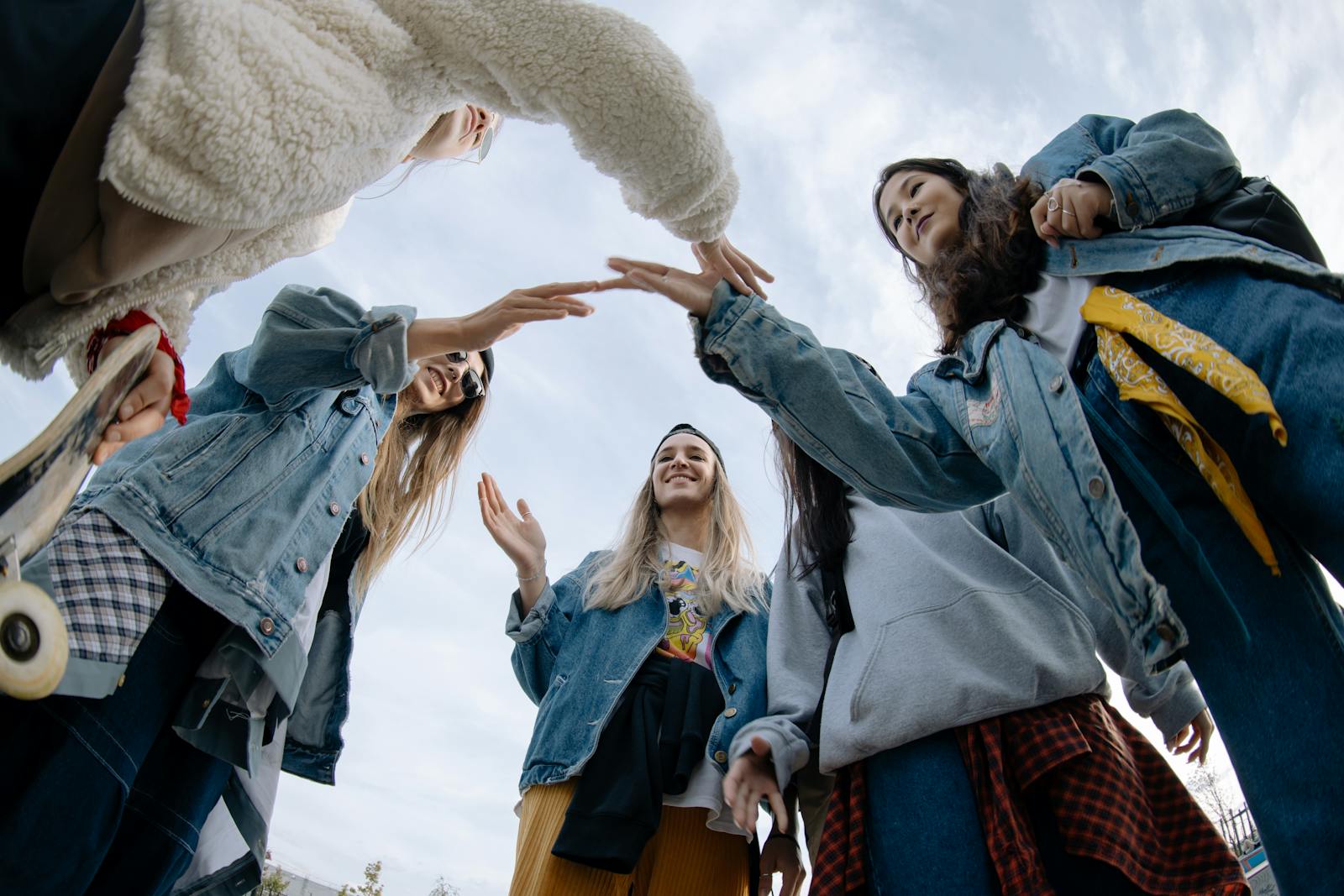 A group of young friends high-fiving each other outdoors, conveying unity and joy.