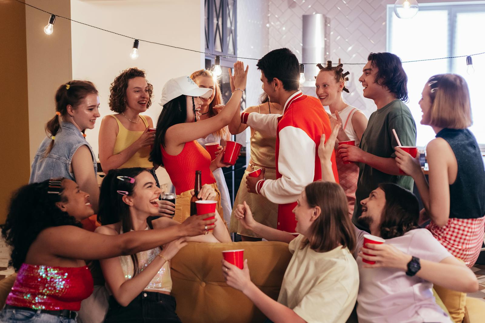 Joyful indoor party scene with friends celebrating and mingling, holding red party cups.