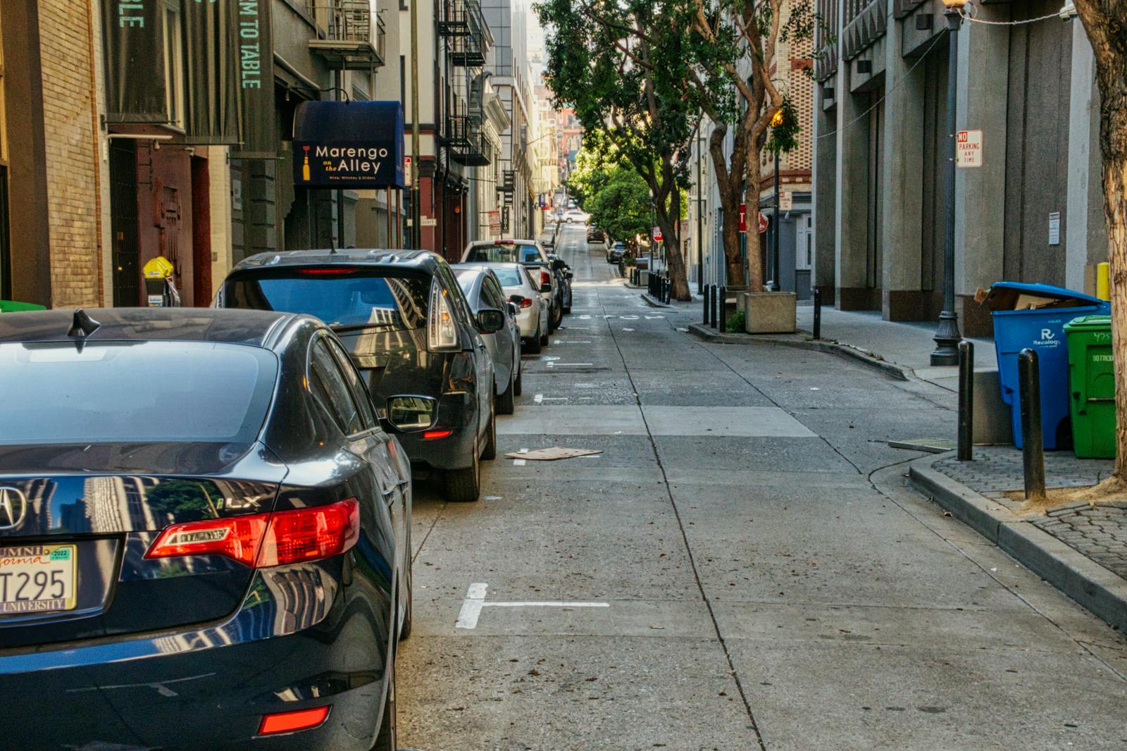 A bustling San Francisco alley with parked cars and urban architecture.