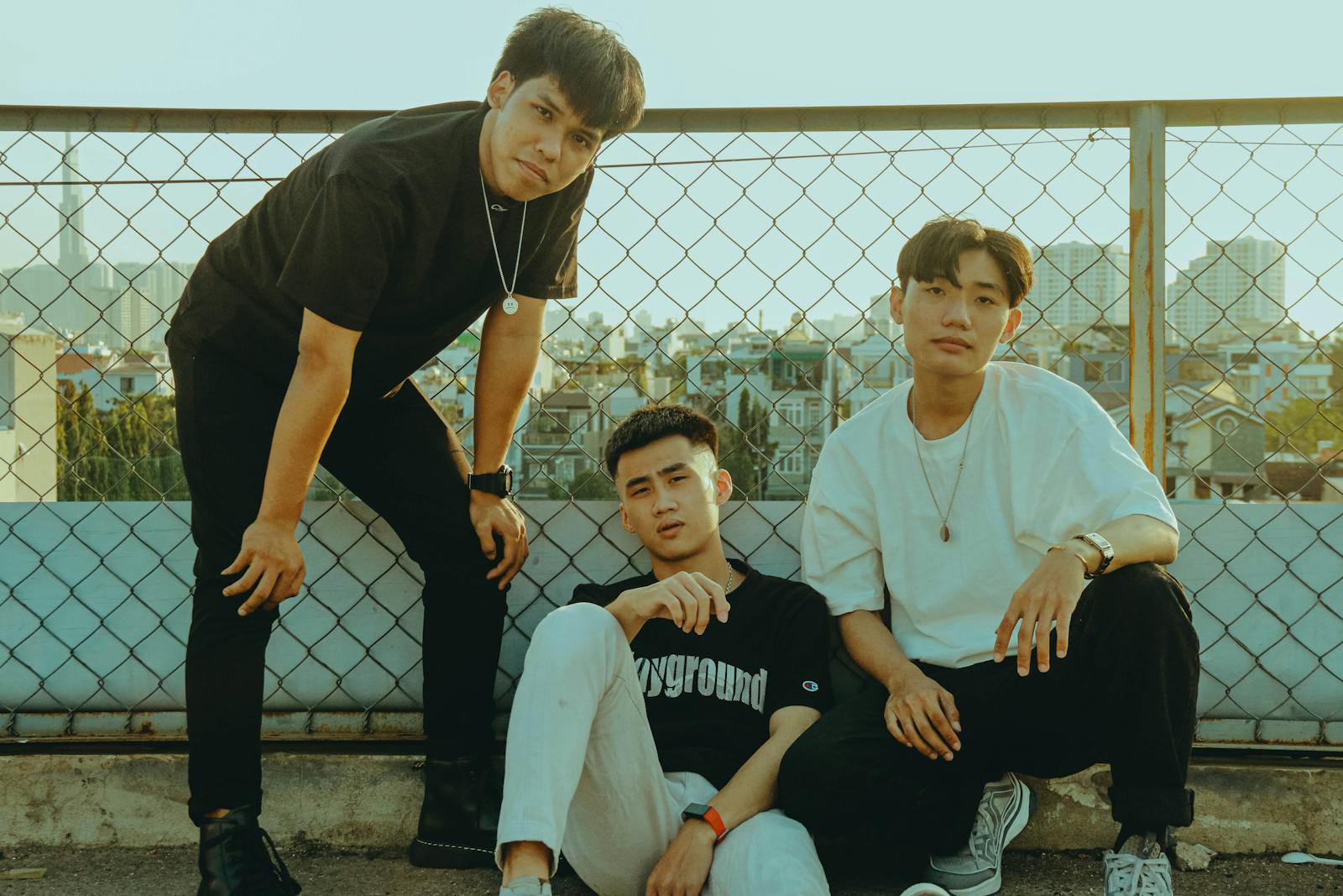Three friends hanging out on a rooftop with a city view behind them.