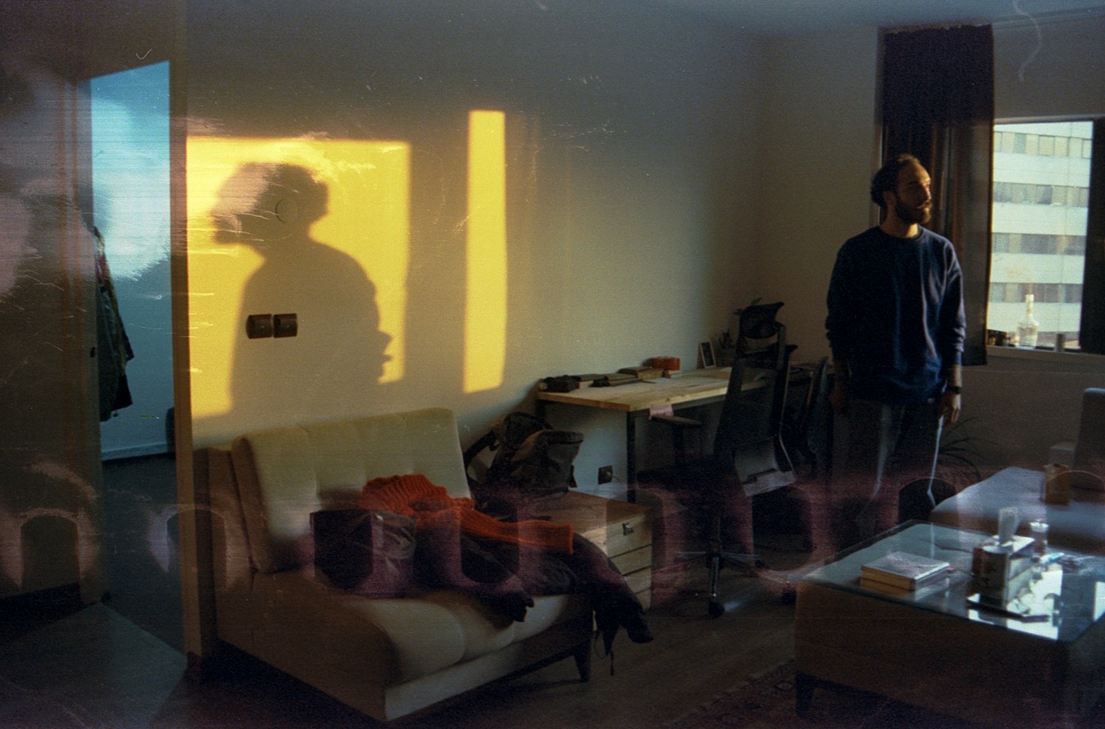 A man stands near shadows in a room.