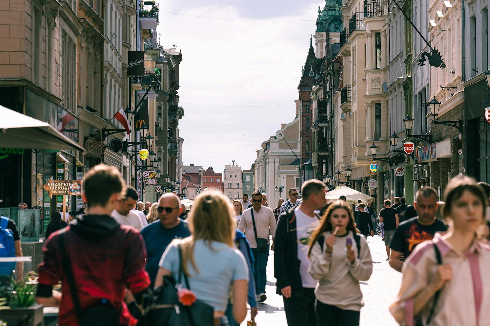 Vibrant urban street scene in Toruń, capturing people and historic architecture on a sunny day.