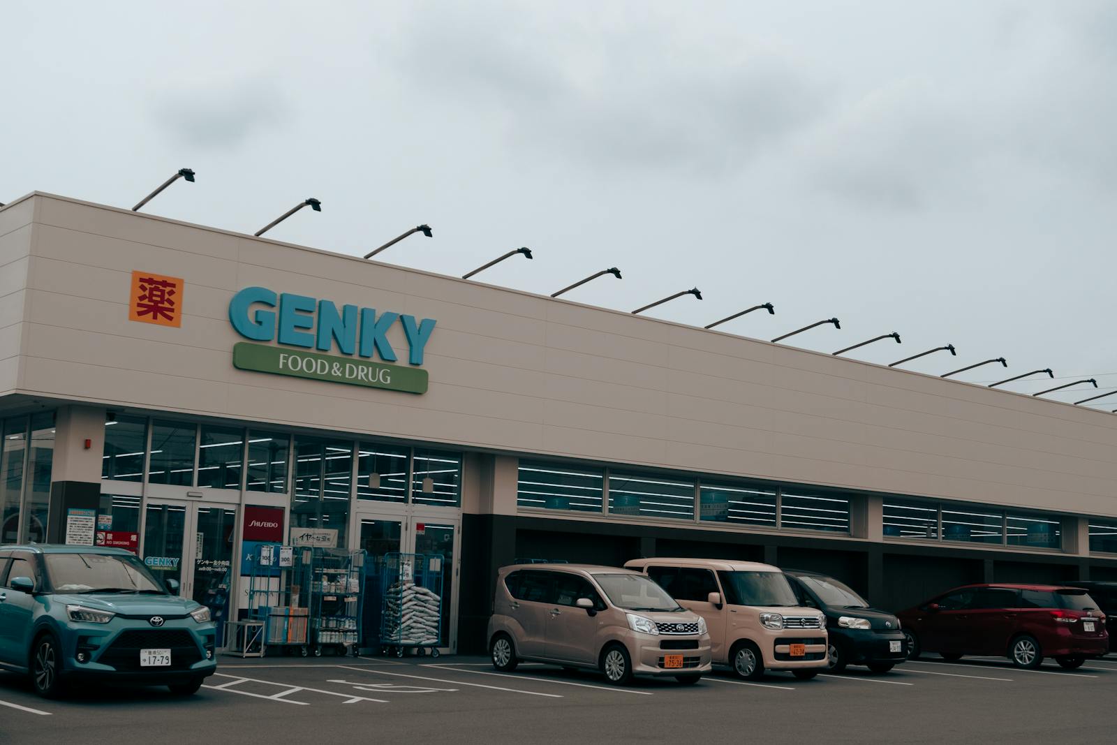 Exterior view of Genky Food & Drug store with parked cars, showcasing urban retail.