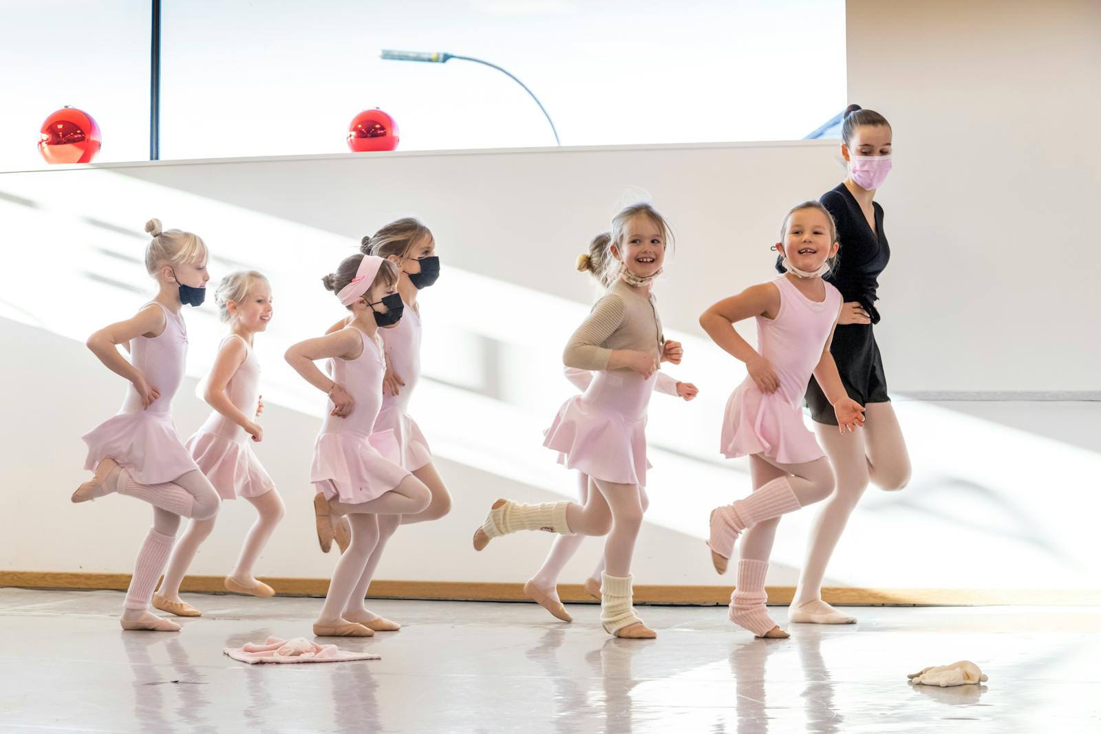 A lively ballet class with young girls in tutus practicing together with an instructor.