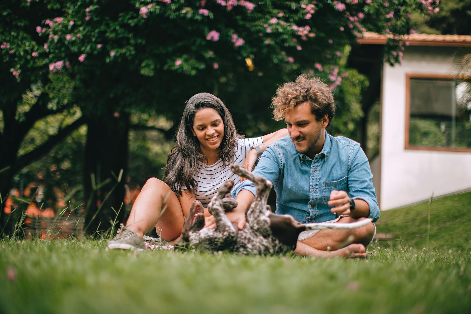 A joyful couple enjoying quality time with their dog outdoors in a park setting.