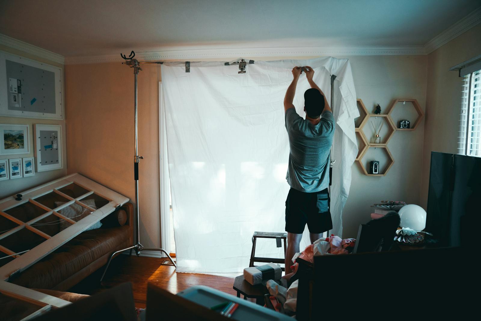 A man prepares a photography backdrop in a cozy home setting, emphasizing interior design.