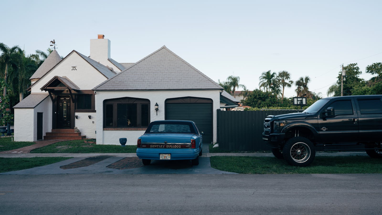A suburban house with parked classic Bentley Bulldog and a modern truck.