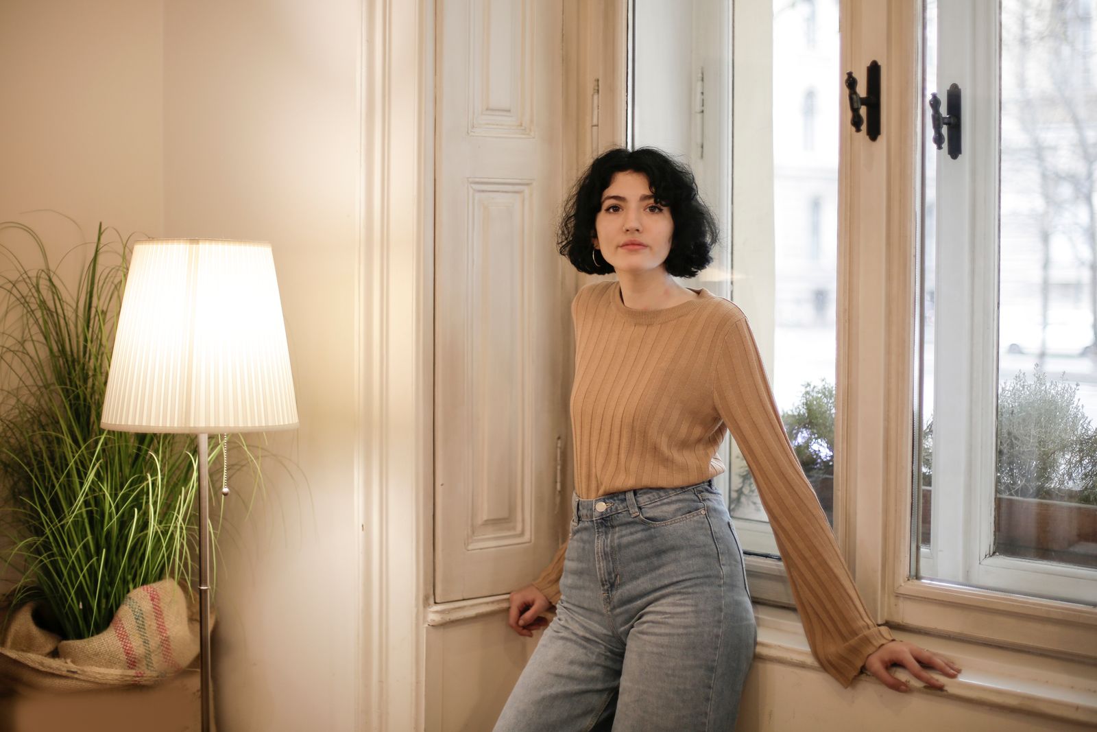 Portrait of a woman in a cozy room with natural light, showcasing relaxed home ambiance.
