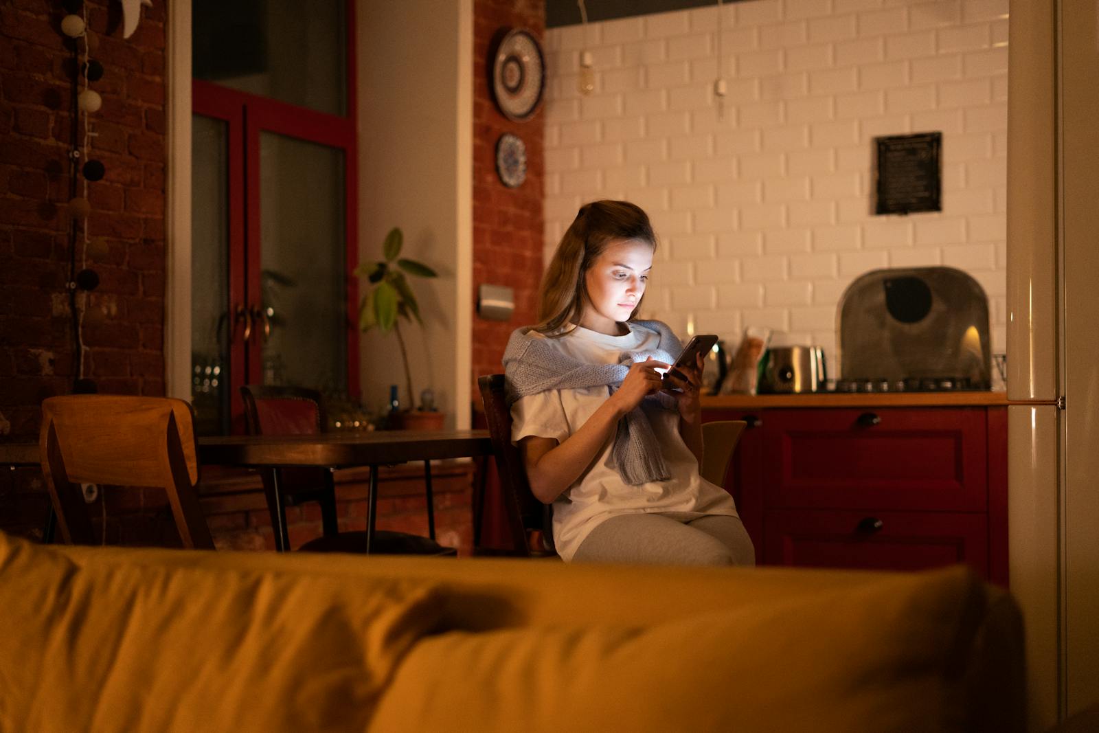 A woman using her smartphone in a cozy home setting during the evening.