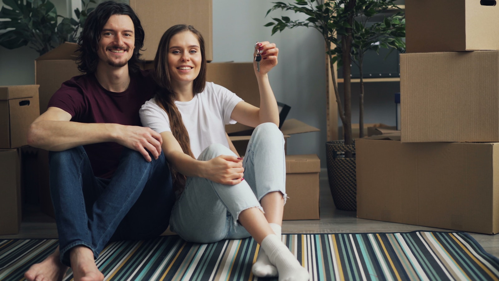 a man and a woman sitting on the floor in front of moving boxes