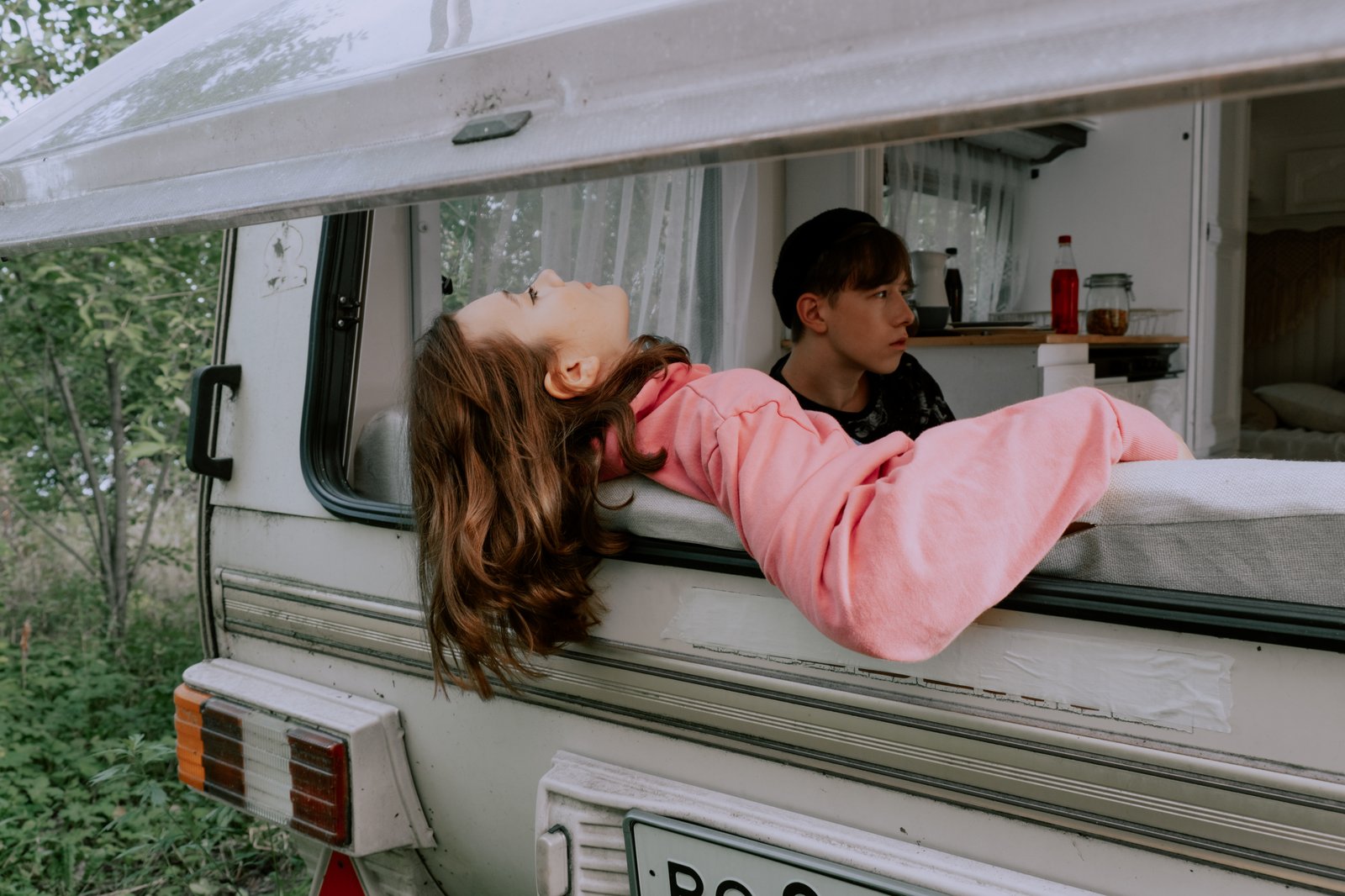 Children relaxing in the window of a camper van, enjoying outdoor leisure time.