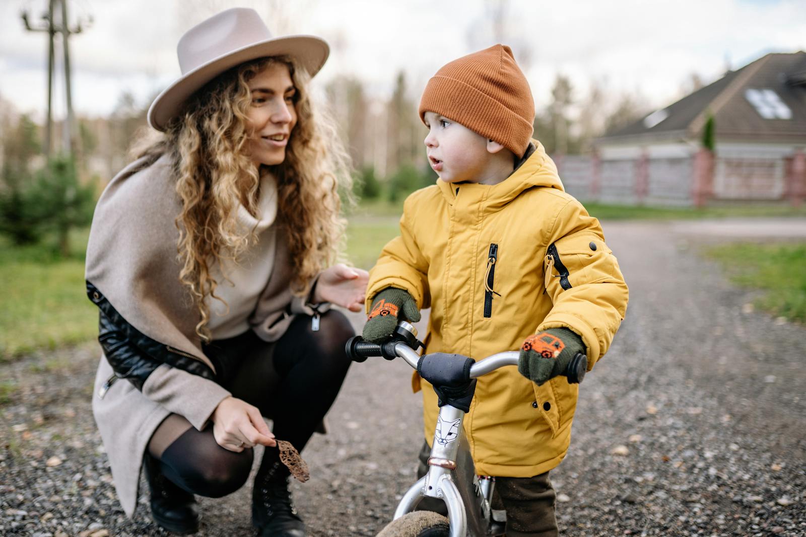 Mother and child spending quality time together with a balance bike in the yard, enjoying a fun outdoor activity.