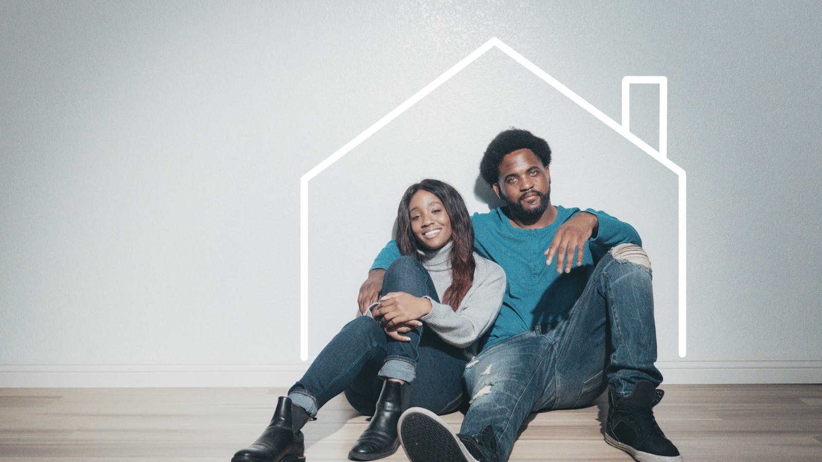 A joyful couple sitting indoors with a house outline, symbolizing their new home.