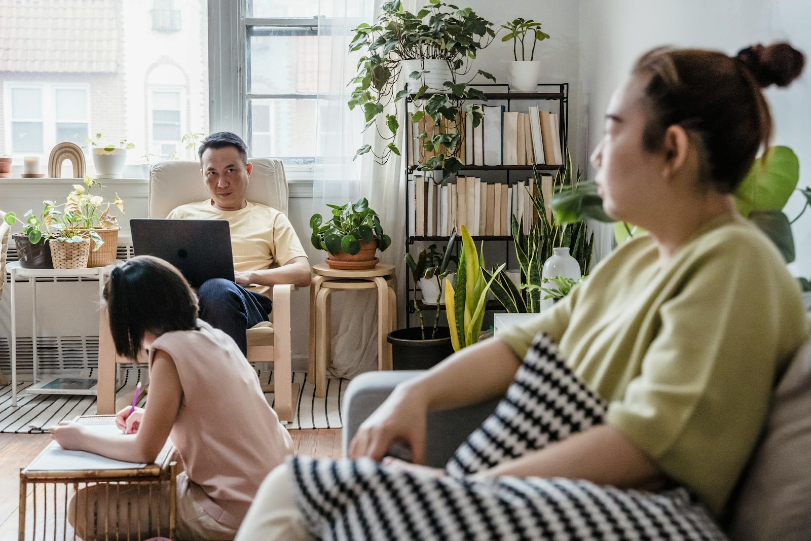 Family spending quality time together indoors with plants, relaxing and working, creating a cozy atmosphere.