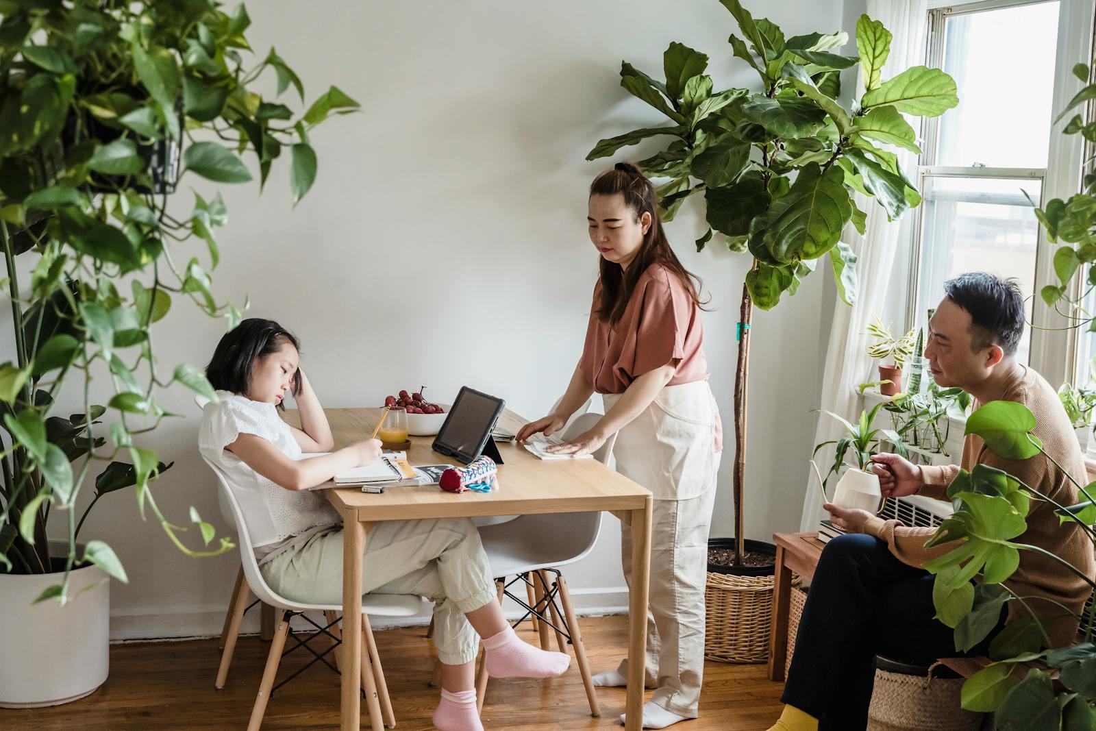 A family enjoys quality time together in a cozy, plant-filled living room.