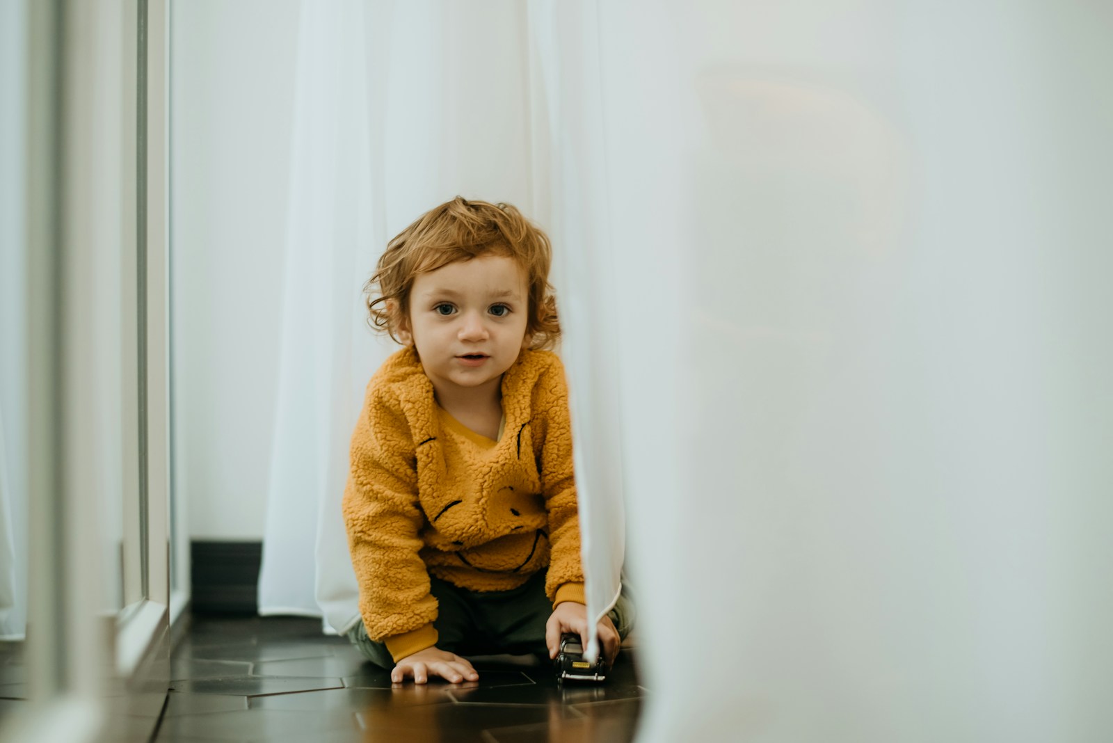 a young child sitting on the floor in front of a mirror