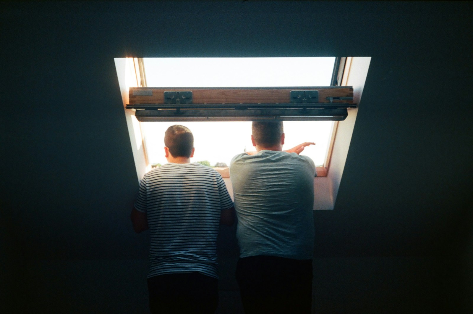 man in white and black striped shirt standing beside window