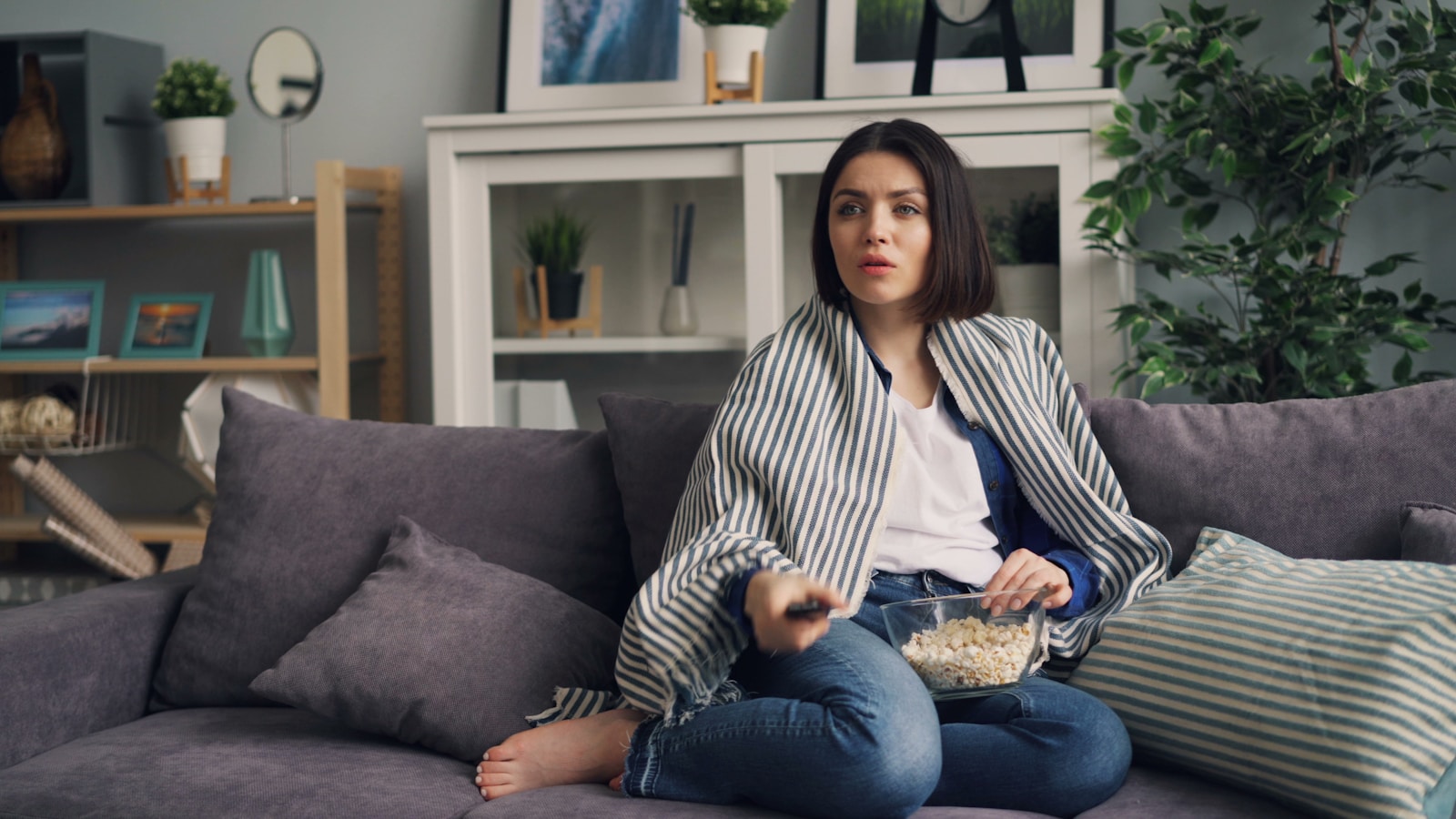 a woman sitting on a couch eating popcorn