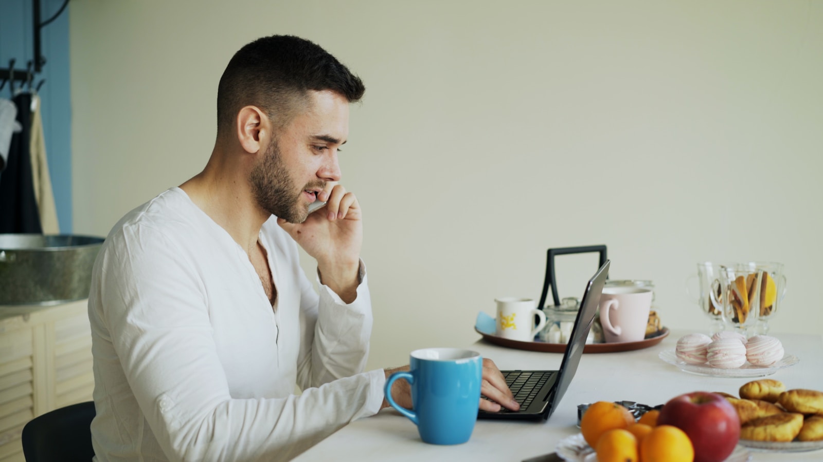Man talking on phone while working on laptop at laptop