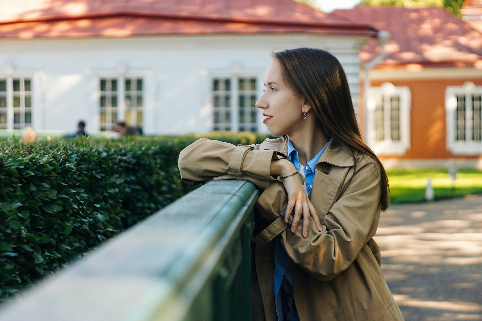 woman in brown coat standing near green plants during daytime