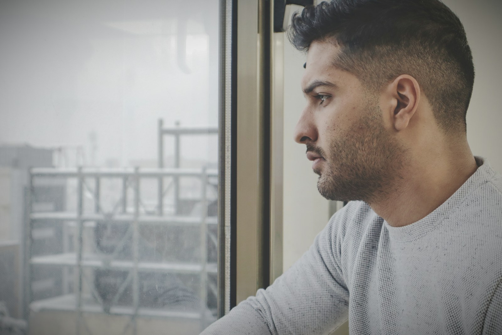 a man looking out of a window in the rain