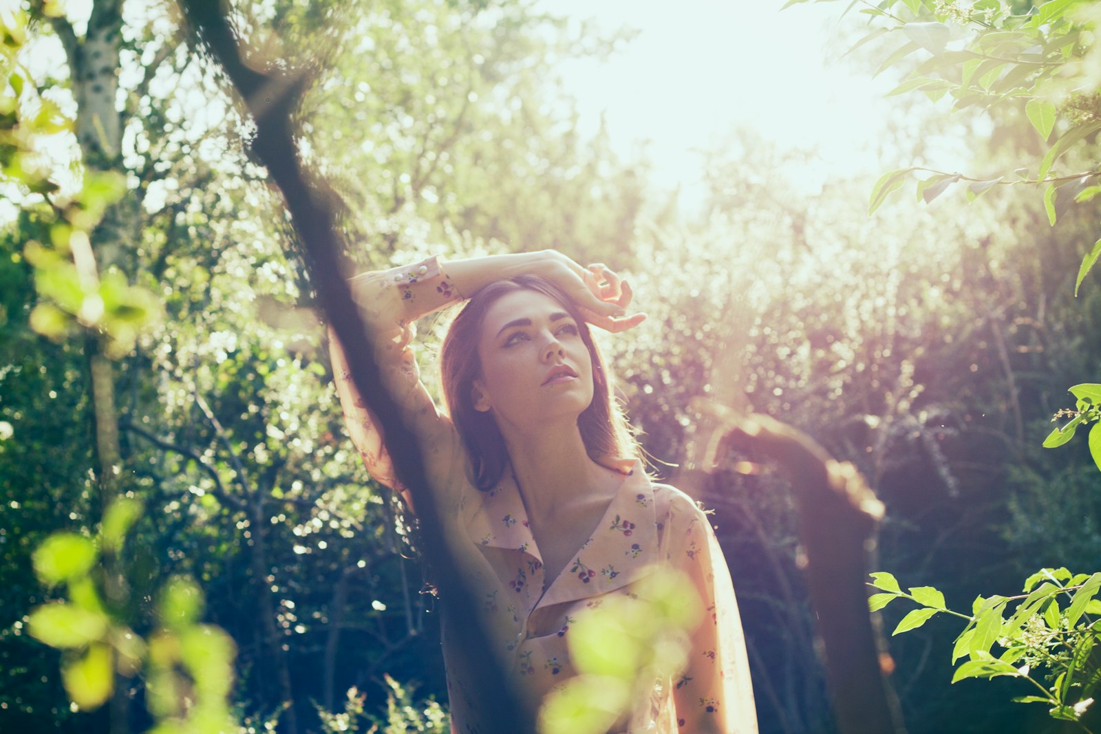 a woman standing in a forest with her hands on her head