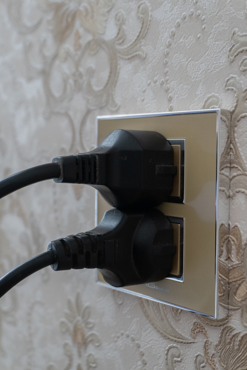 Two black electrical plugs inserted into wall socket