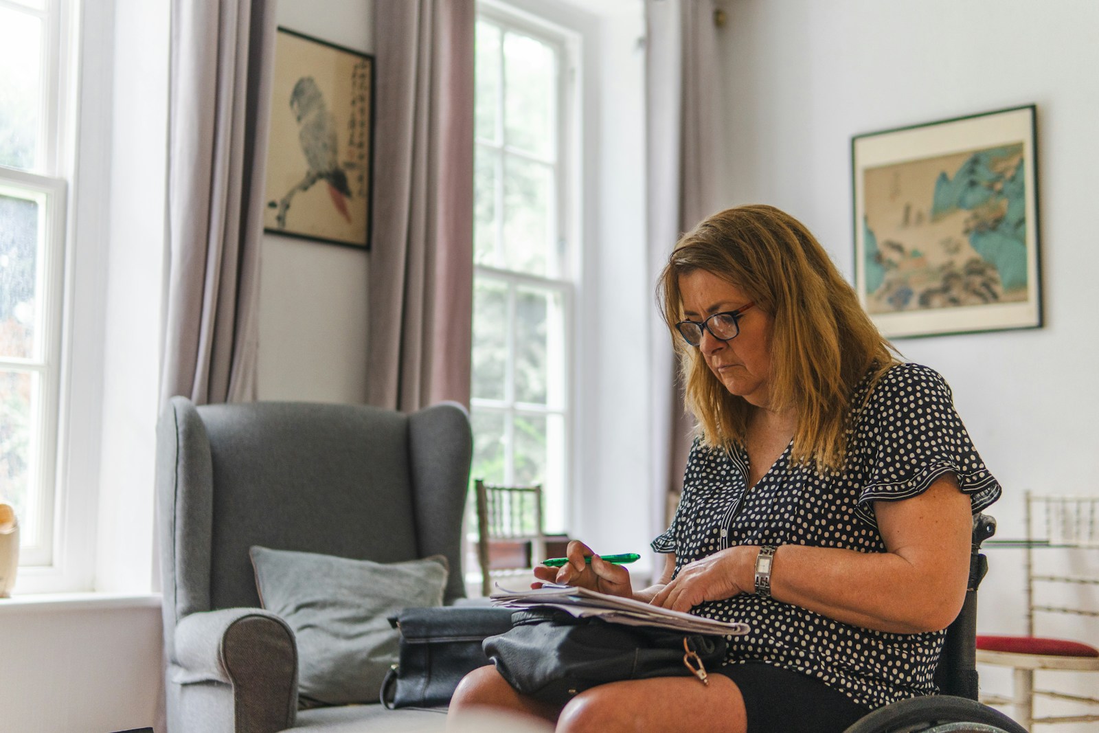 Woman sitting in a chair looking at papers.