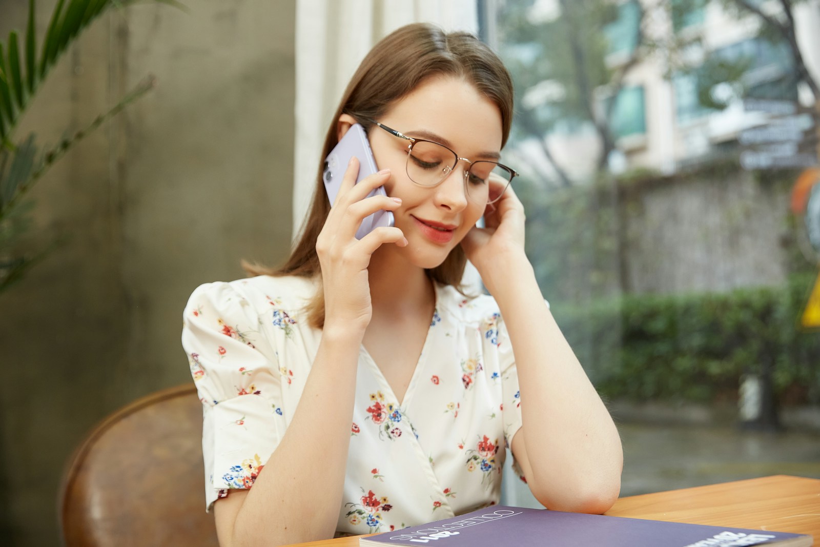 A woman sitting at a table talking on a cell phone