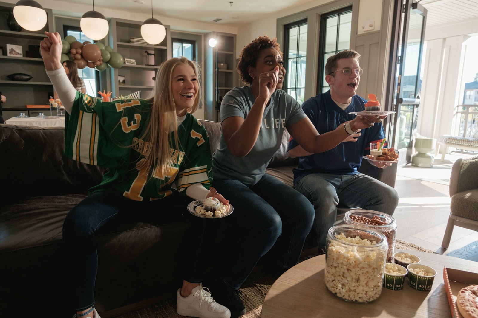 Friends excitedly watching a sporting event at home