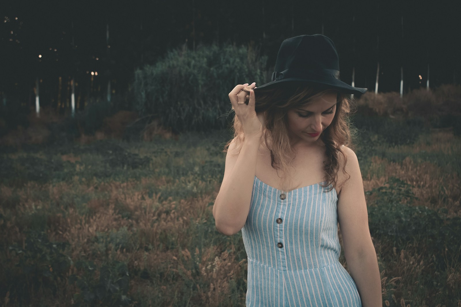 woman holding her hat while looking down