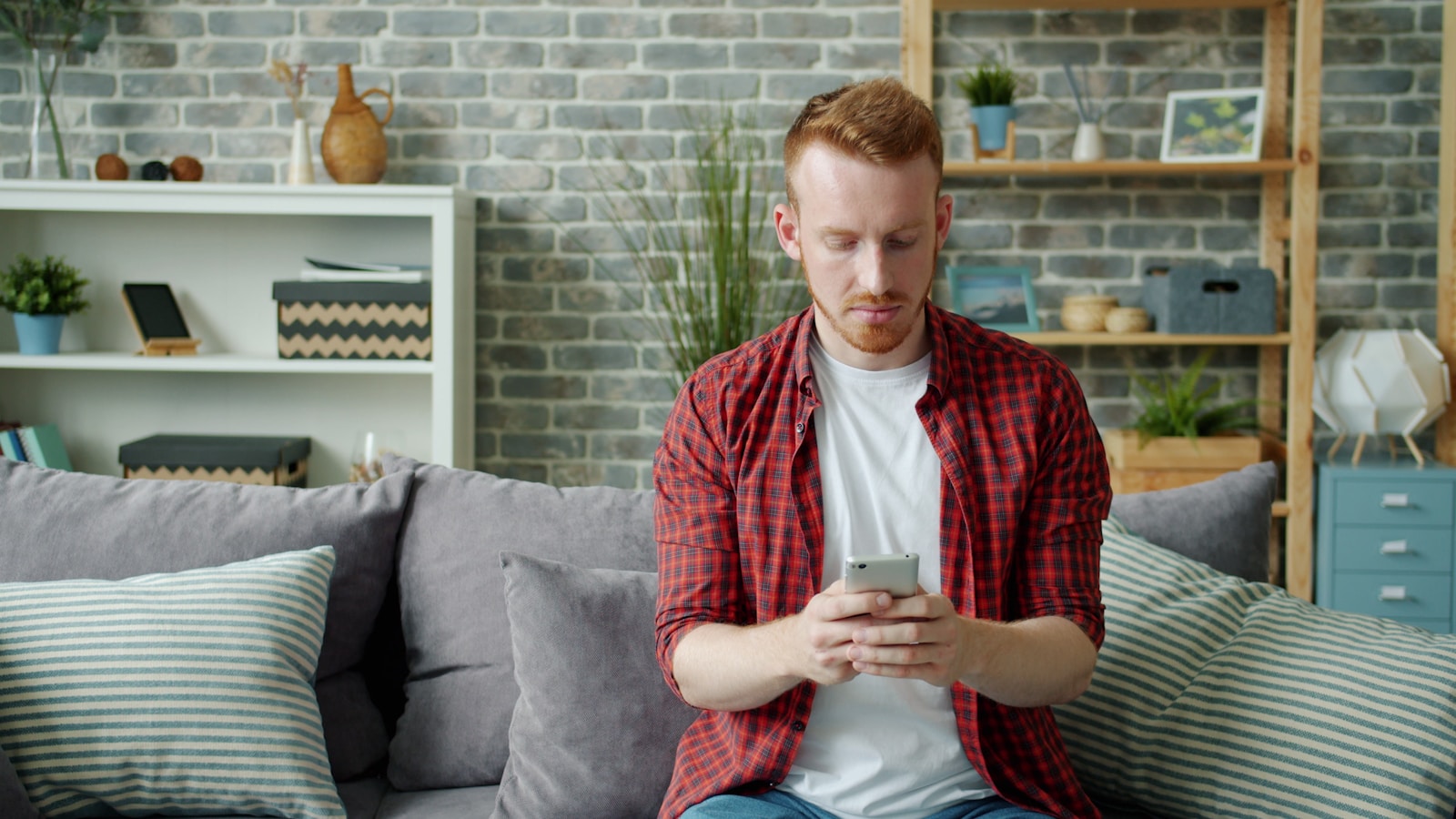 Man sitting on couch using smartphone