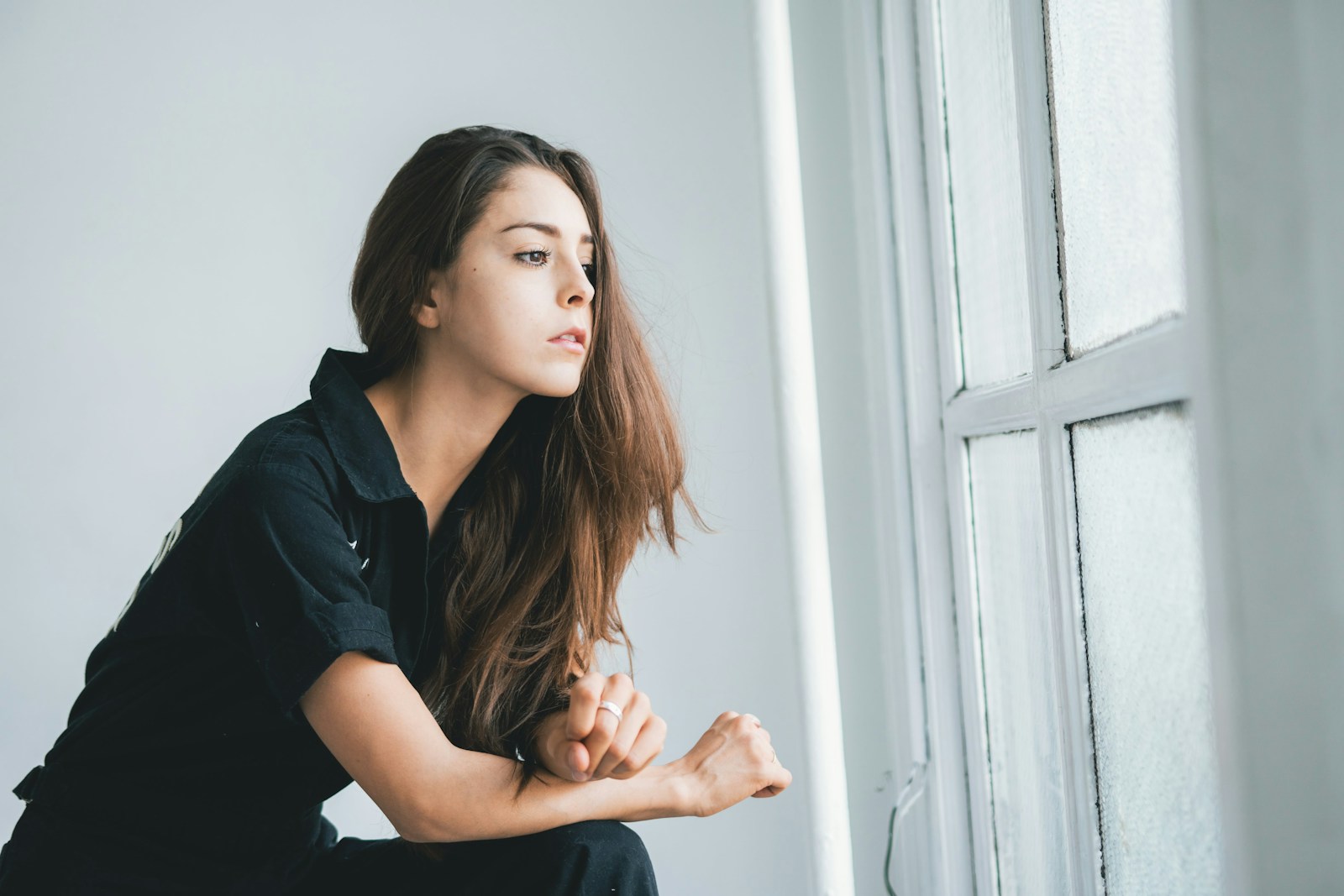 woman in black shirt leaning on white wall