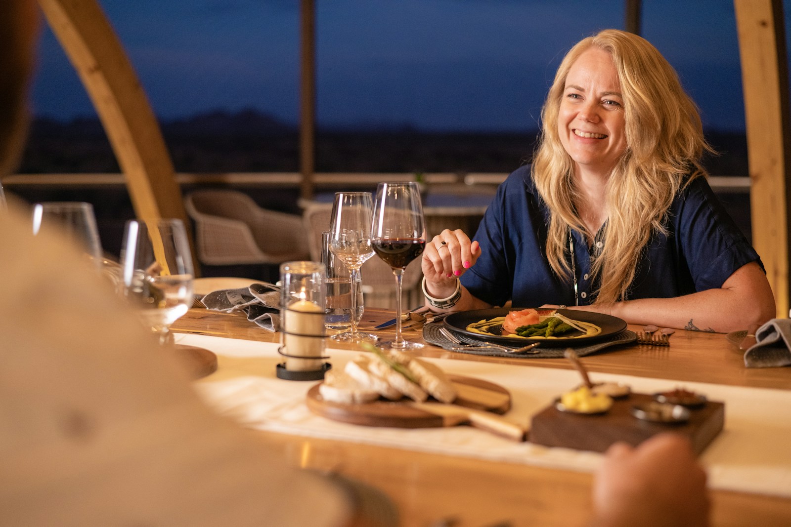 a woman sitting at a table with a glass of wine