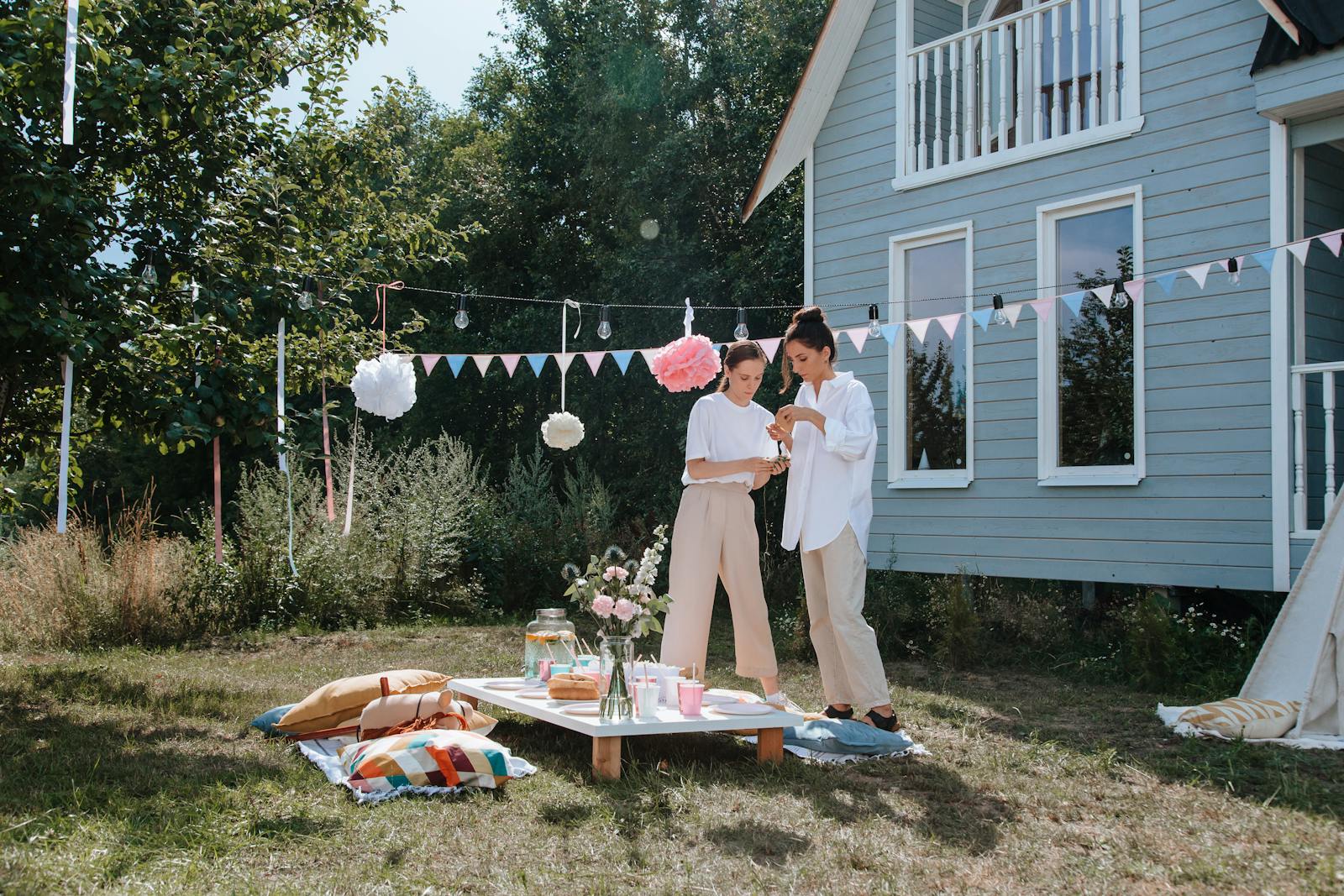 A cozy outdoor summer party setup with decorations, food, and friends enjoying the day.