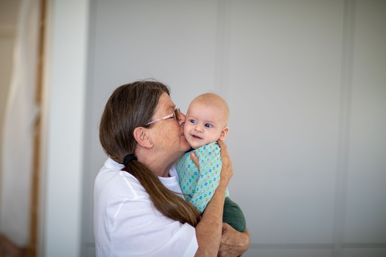 A joyful moment between a loving grandmother and her smiling grandchild indoors.