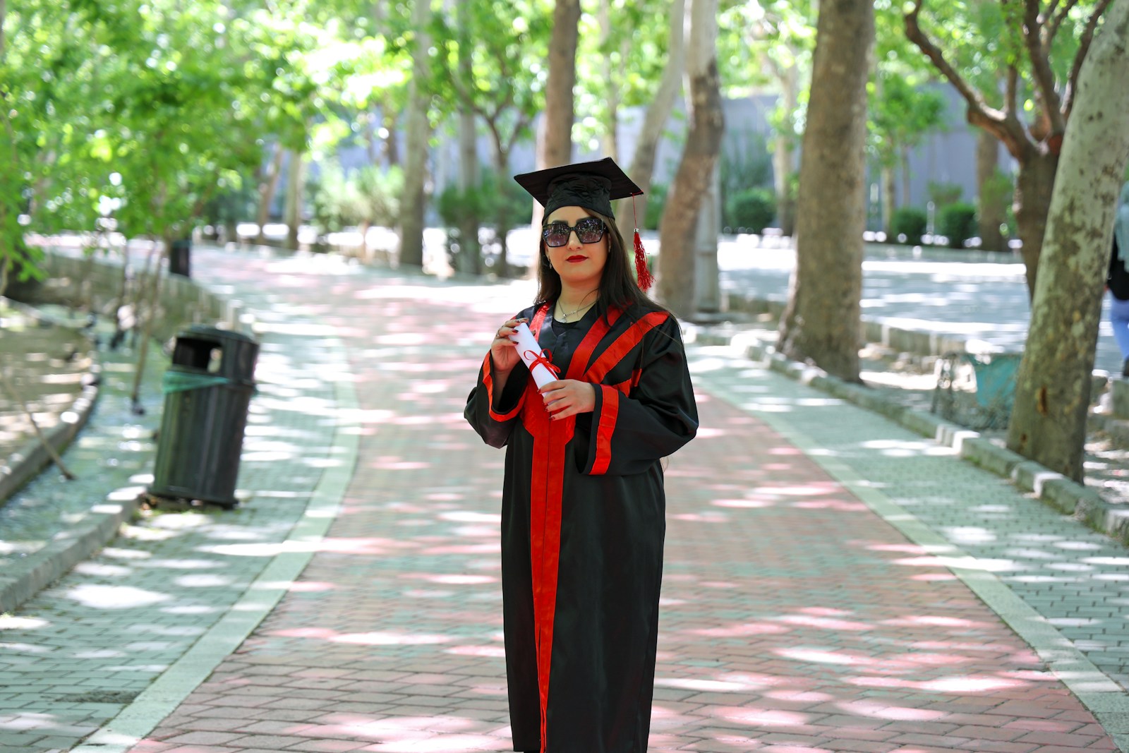 A woman in graduation gown and cap stands outside