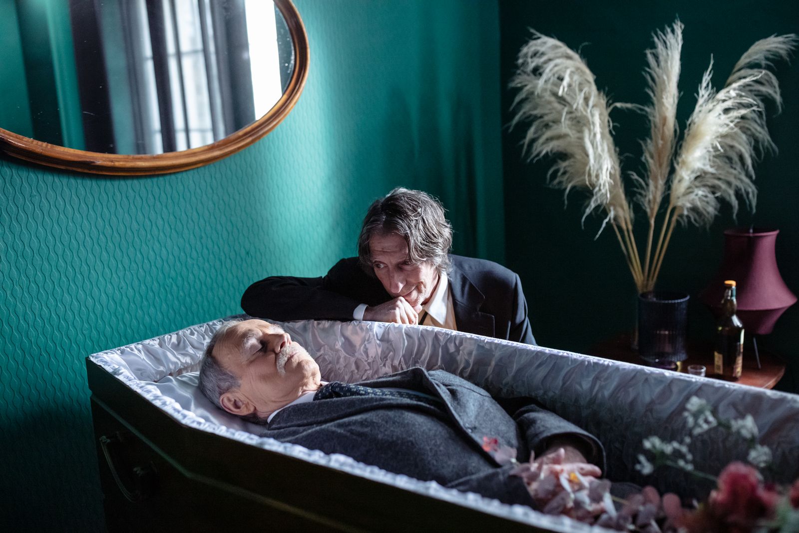 A grieving man paying his last respects to the deceased at a funeral.