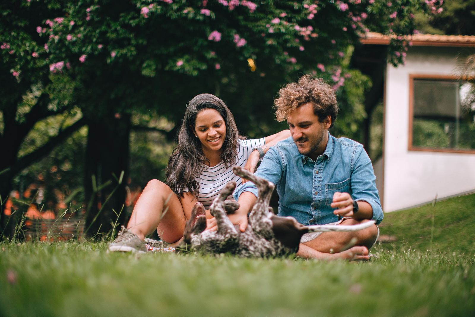 A joyful couple enjoying quality time with their dog outdoors in a park setting.