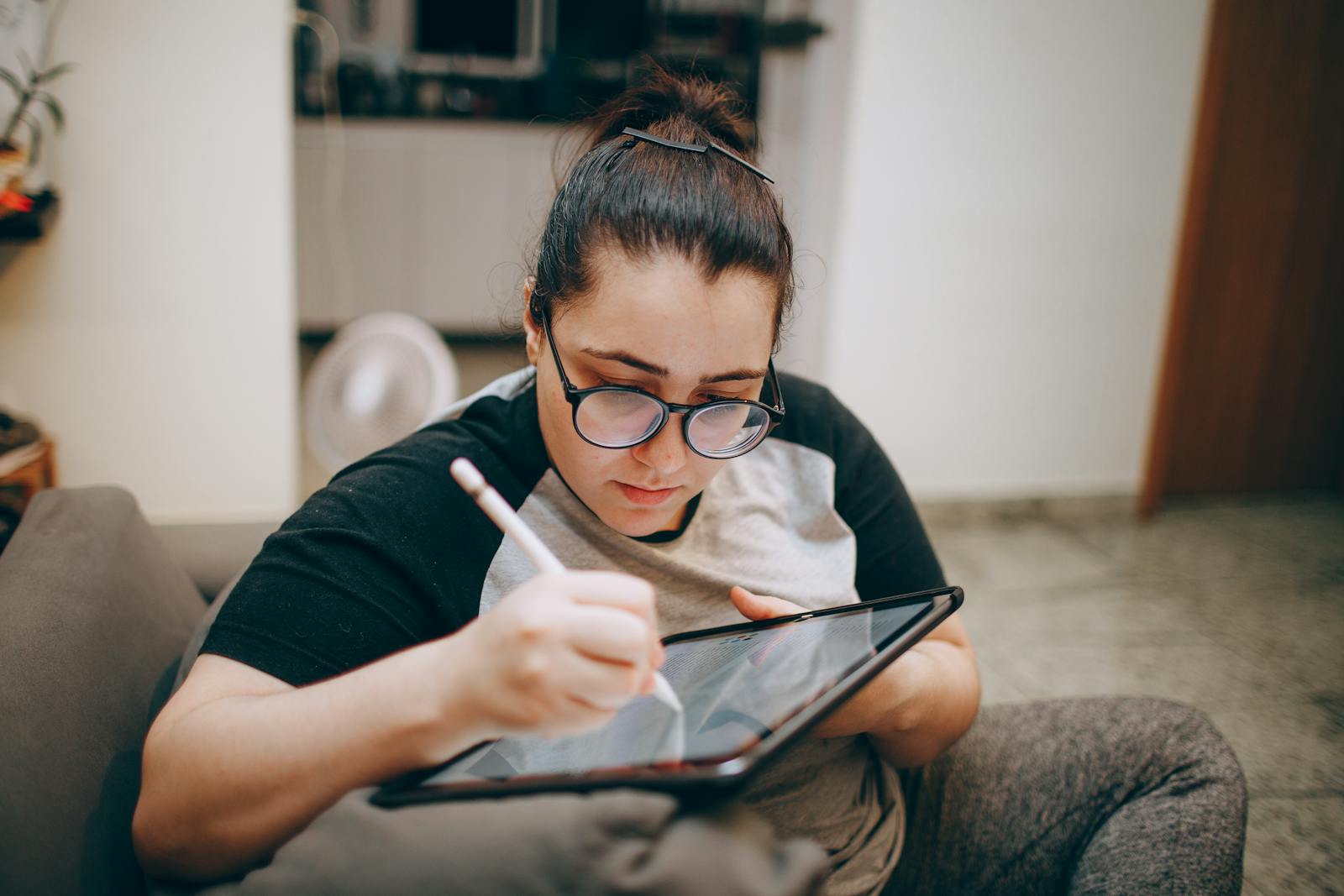Woman deeply focused on digital art creation using a tablet and stylus indoors.