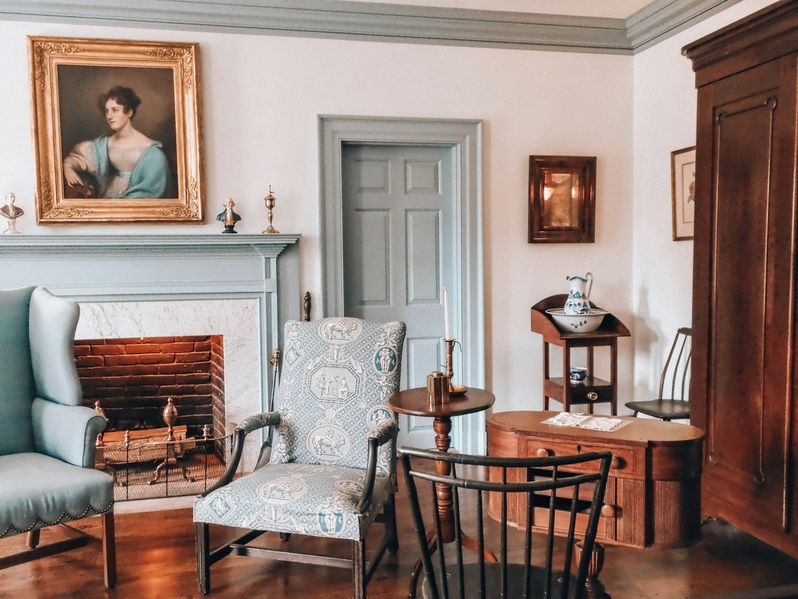 An antique room with a fireplace, painting, and traditional furniture.
