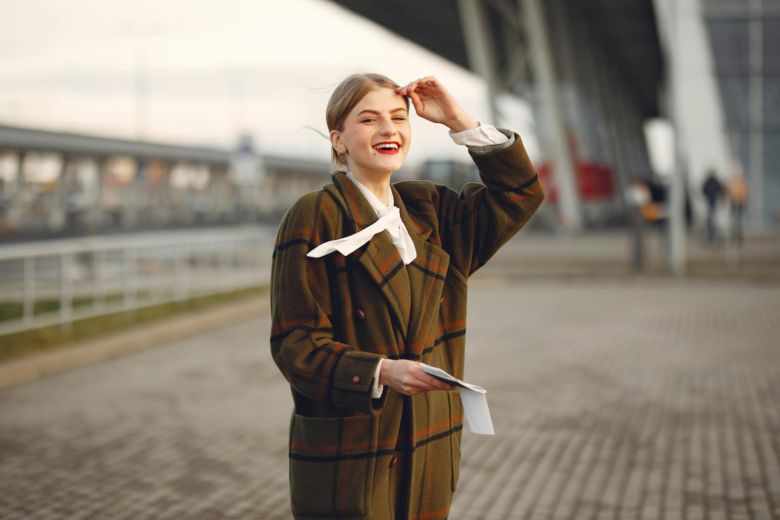 A happy woman in a plaid coat smiling outdoors, exuding warmth and style.