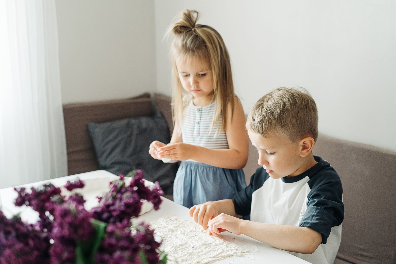 Young boy and girl playing with dough at a table, enjoying a fun indoor activity.