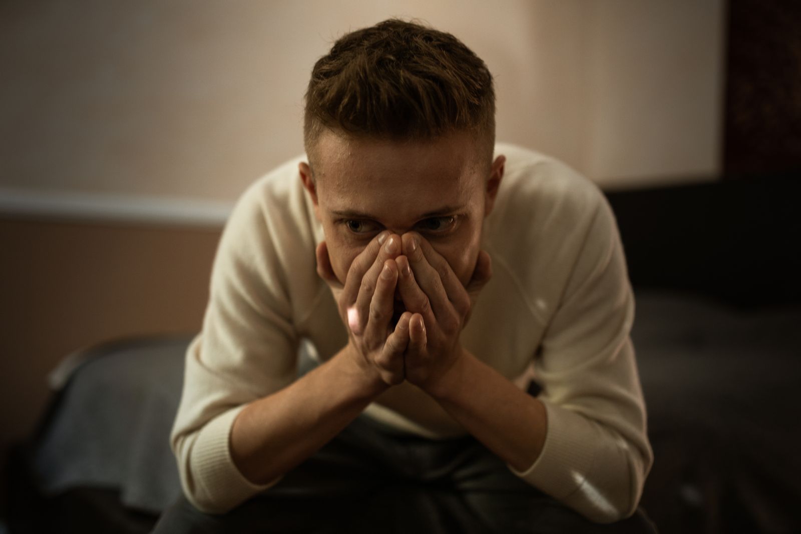 A worried man indoors covering his face with hands, depicting stress or contemplation.