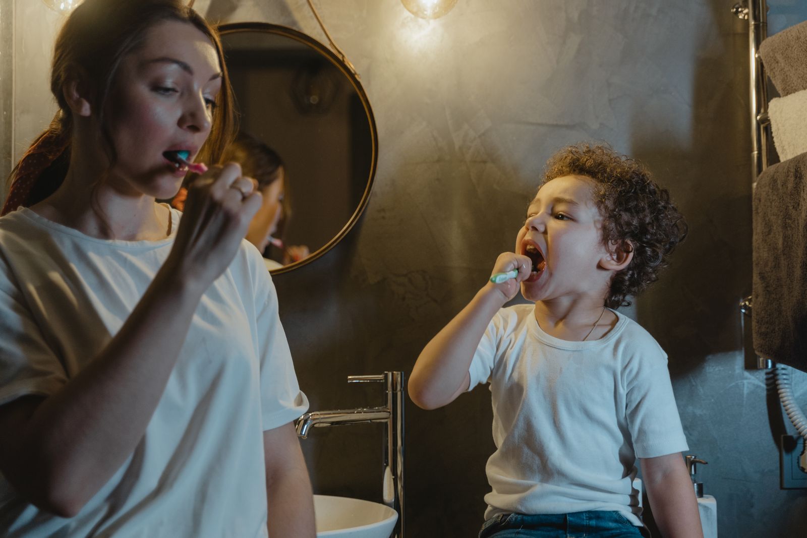 Mother and son bonding in bathroom during teeth brushing routine.