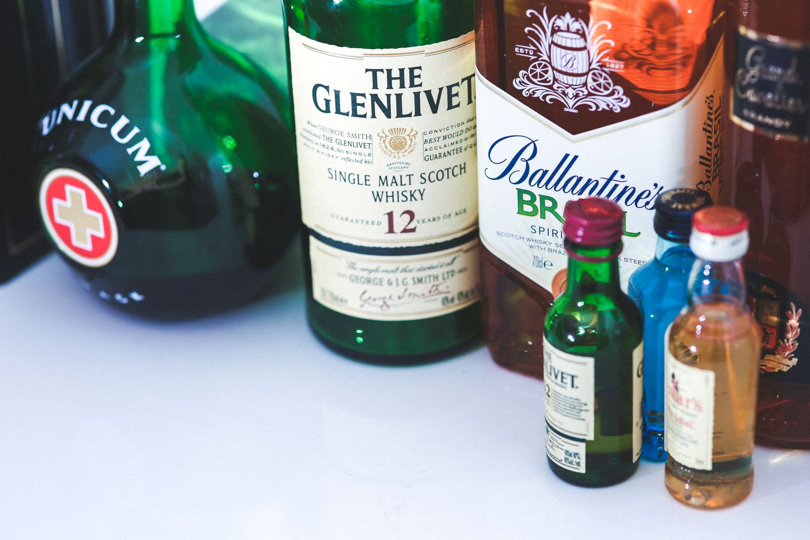 Various whiskey and liquor bottles arranged on a bar indoors, showcasing labels and designs.